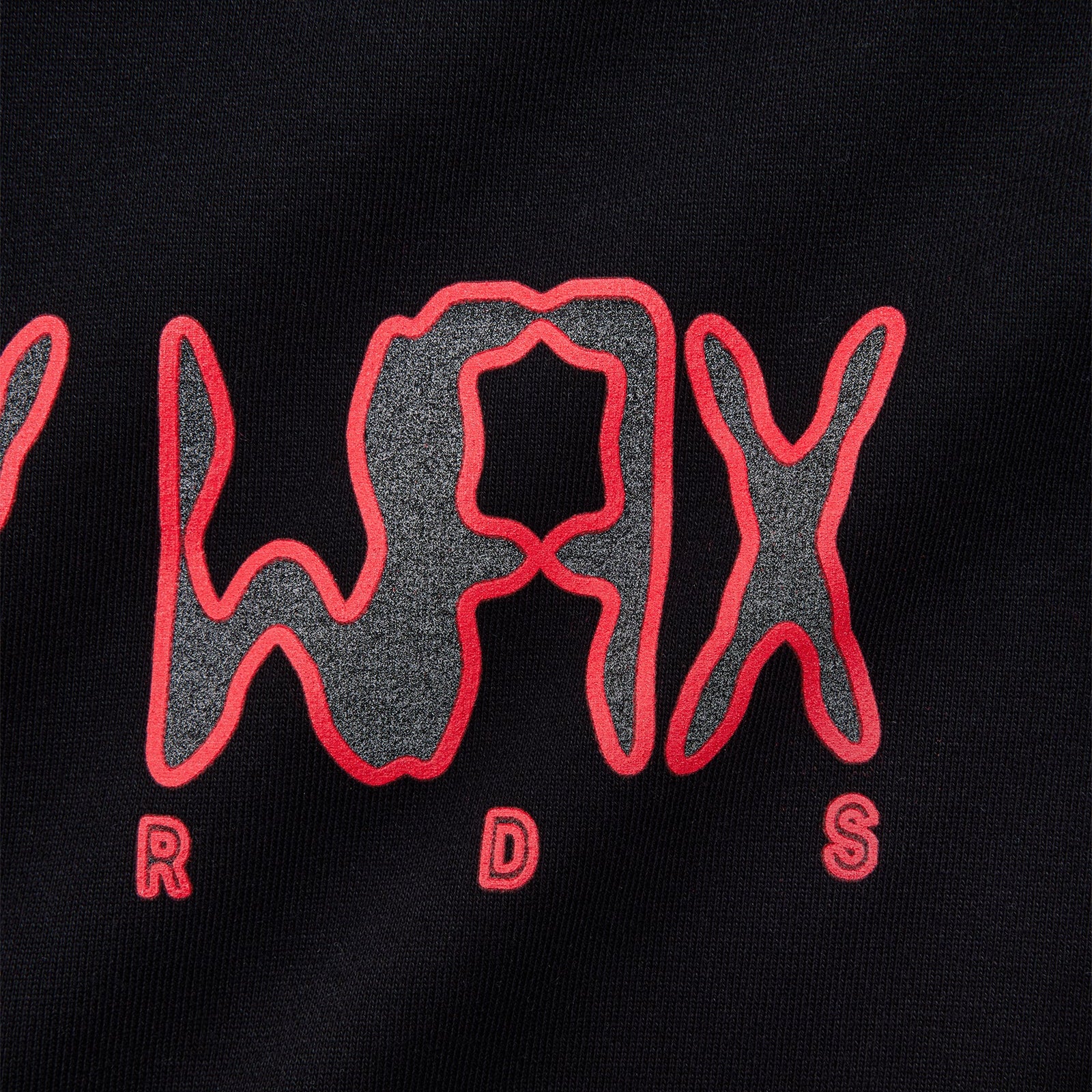 Close-up of a black fabric garment featuring a stylized red and reflective graphic